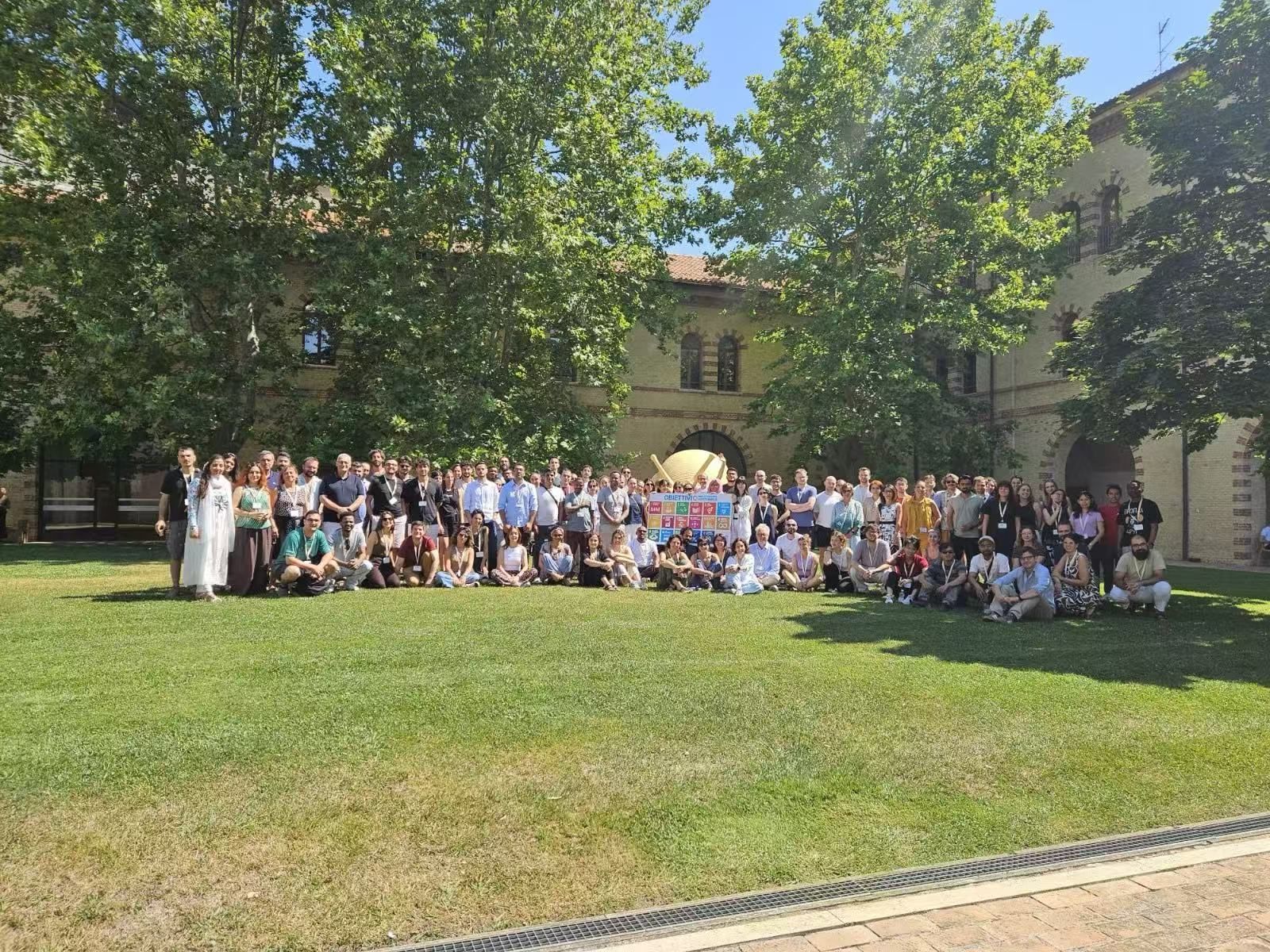 Large group of researchers photographed in a courtyard beside a Sustainable Development Goals banner