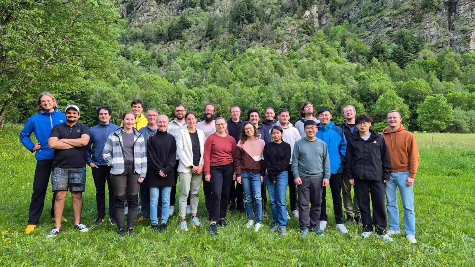 Group photograph of workshop participants in an alpine meadow in France